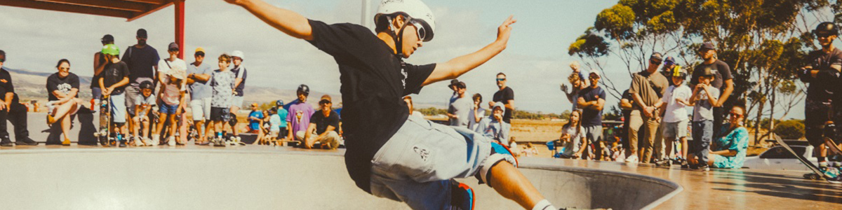 Man on a skateboard skating up a ramp while a crowd of people watch him