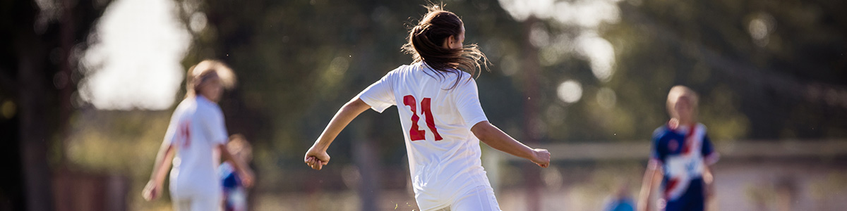 Girl on a soccer pitch with teammates in the background