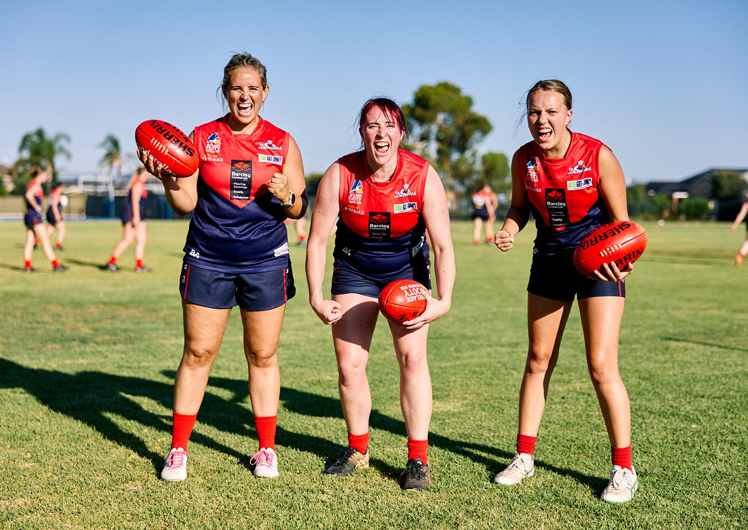 Three female football players holding footballs